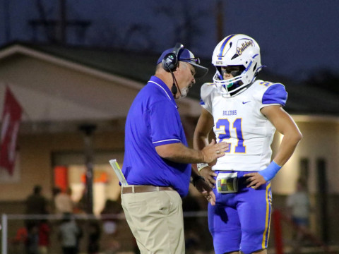SUPERINTENDENT BECOMES SUPERCOACH Craig Hamilton (left) of Spur—standing in for head coach Tate Clark during an extended illness—advises son JD Hamilton, #21, on a play. DANA CONRAD PHOTO